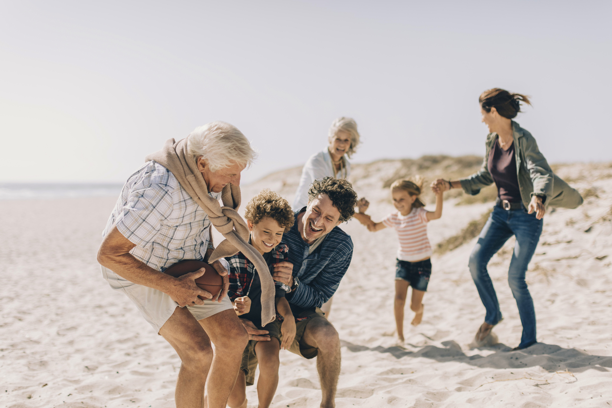 Lekefull storfamilie på stranden. Foto