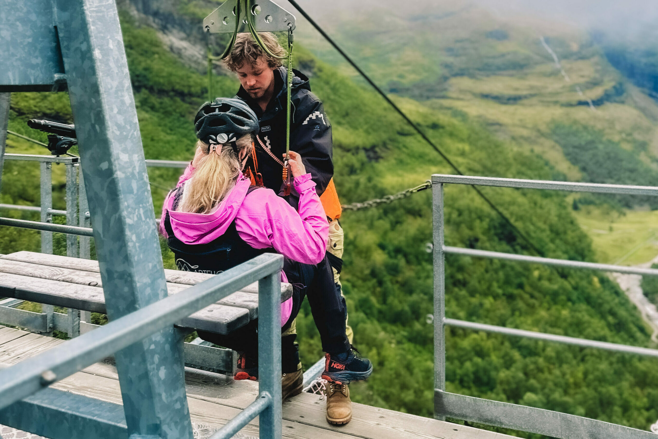 En dame i rosa jakke som skal ta zipline. Foto