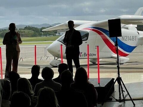 Mennesker som er med på åpningen av flyruten mellom Stavanger og Bergen, med et elektrisk fly fra Bristow Norway i bakgrunnen . Foto.