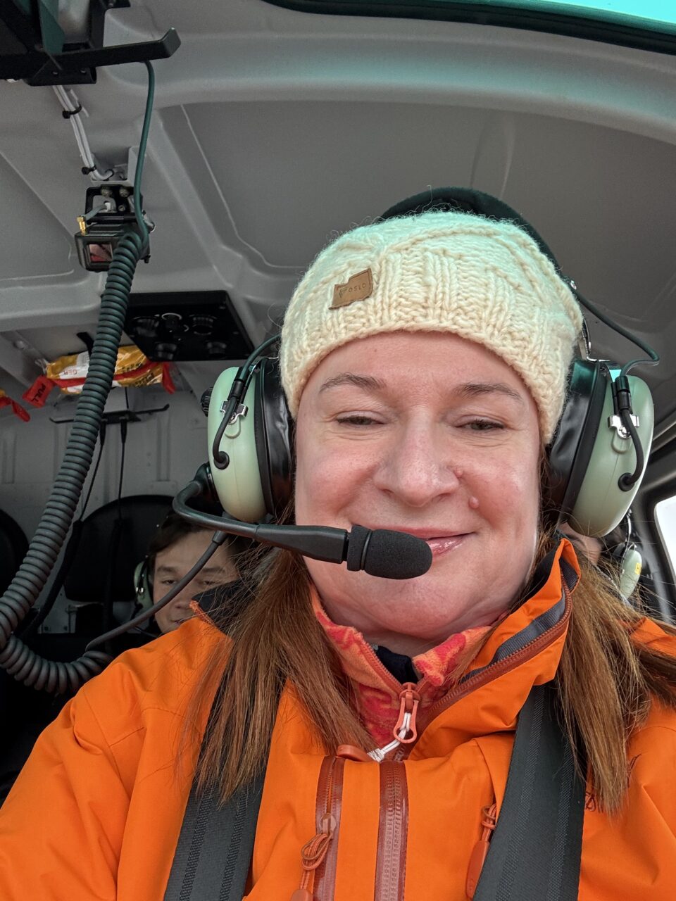 En dame som smiler til kameraet inni et helikopter. Foto