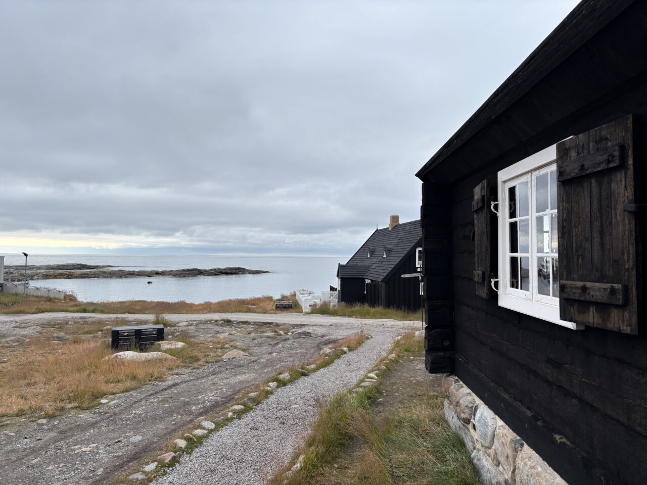 Gamle, brune trehus på en gangvei mot havet. Foto 