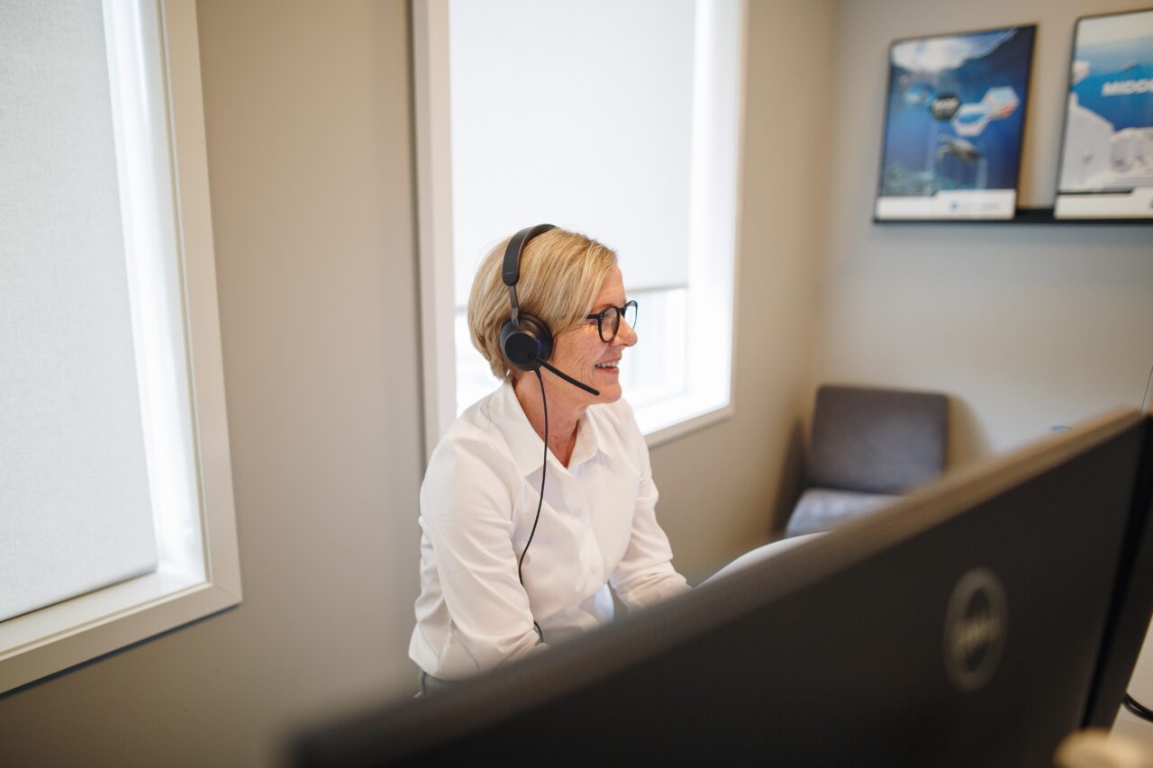 Blid dame som prater i headset. Foto