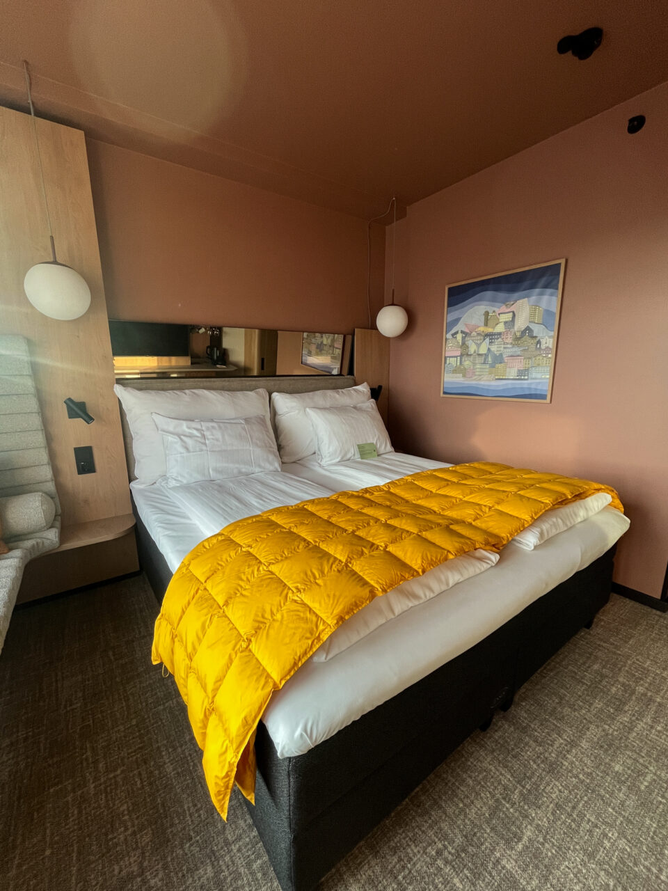 Hotellrom med seng, lamper og et bilde på veggen. Foto