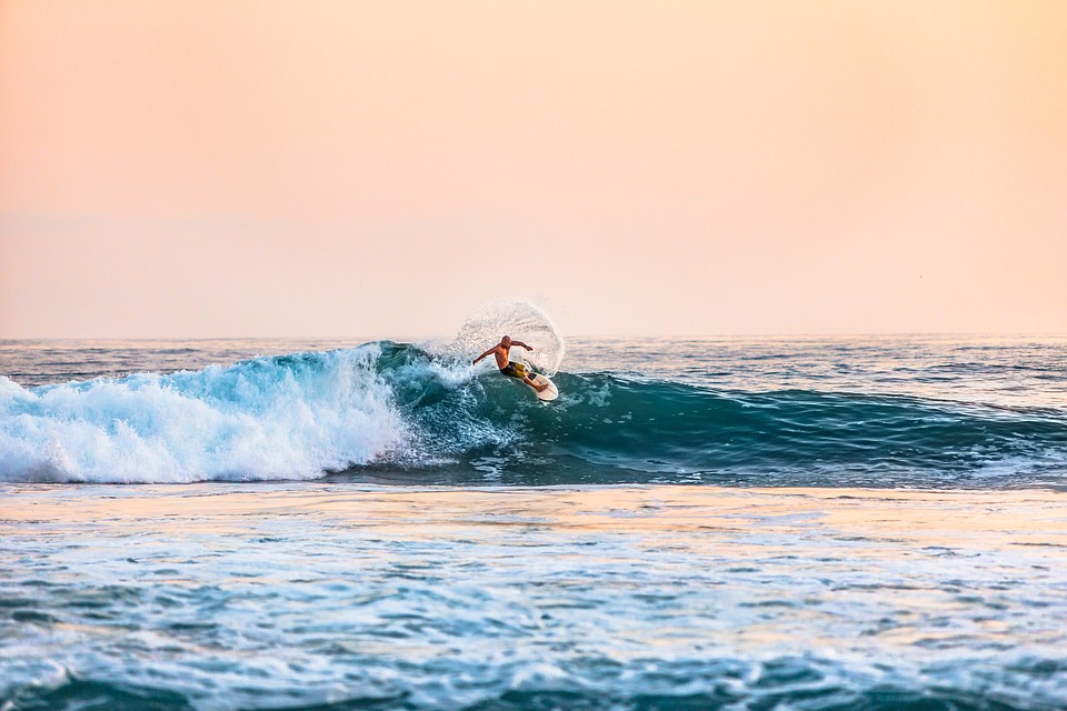 Mann surfer ute på bølgene