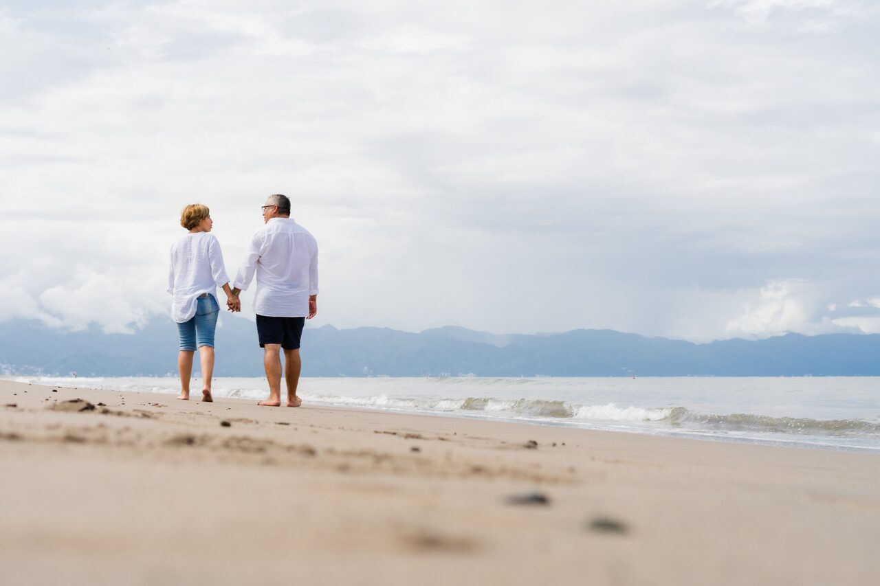 Par holder hender mens de går tur langs stranden