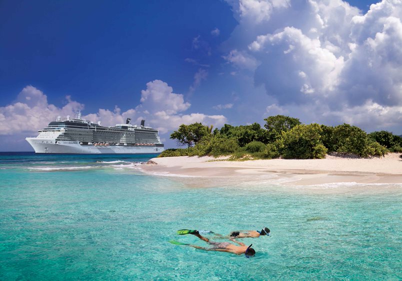To turister som snorkler på stranden, og med cruiseskipet Celebrity Cruise liggende i bakgrunnen