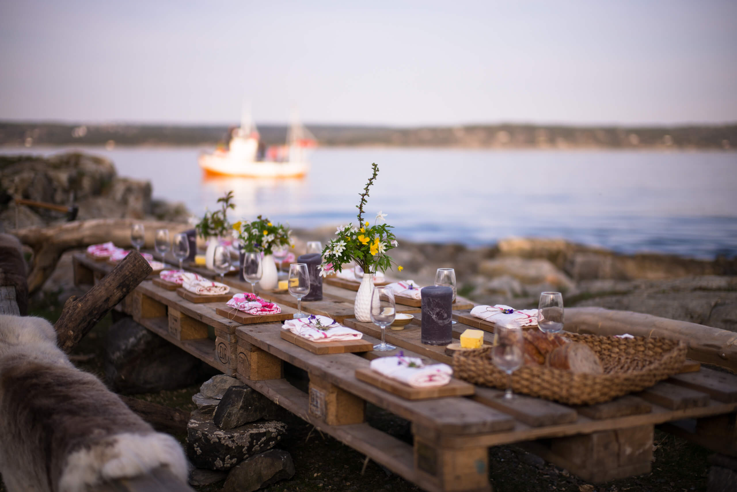 Langbord dekket med dekketøy og friske blomster, ved strandkanten i soldnedgang