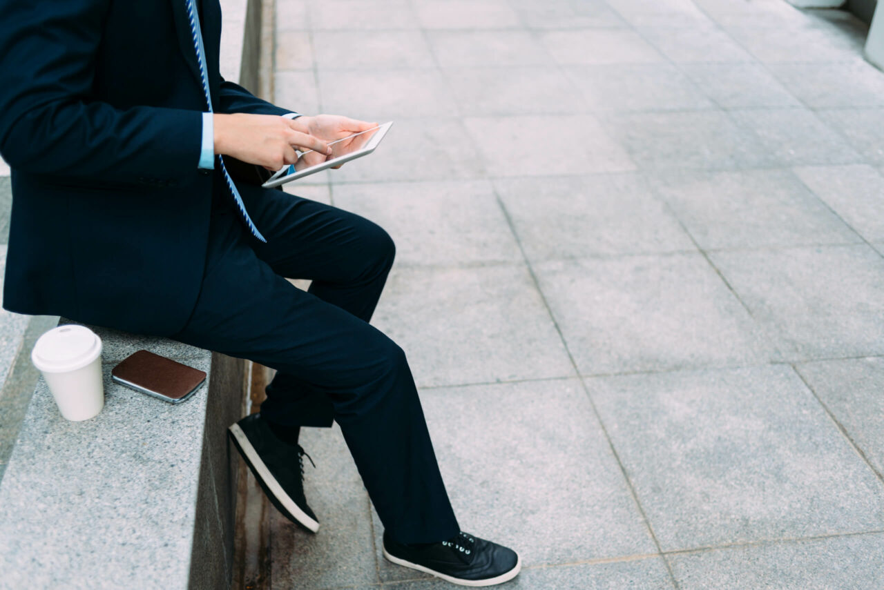 Man sitter på benk mens han ser ned på mobilen