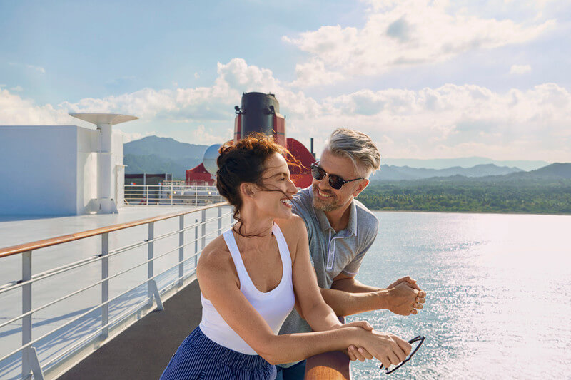 Et par om står ved siden av hverandre og ser utover havet om bord på Queen Mary 2. Foto.