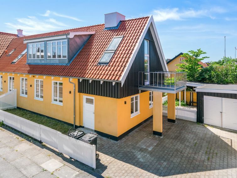 Gult feriehus over to etasjer midt i byen. Foto