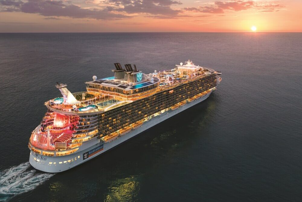 Cruiseskipet Allure of the Seas seiler på åpent hav mot solnedgangen