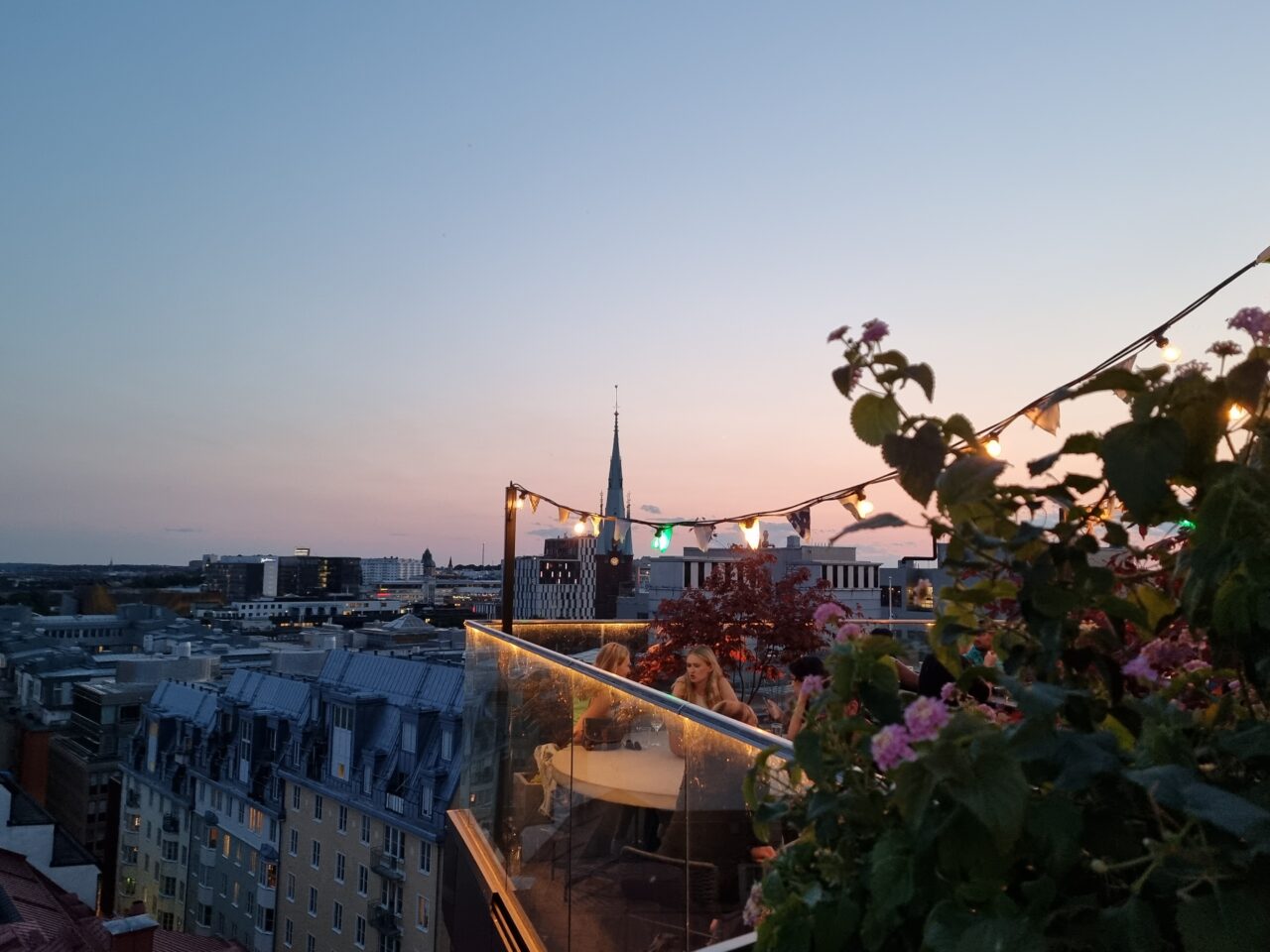 Solnedgang med koselige lys og blomster på takterrassen