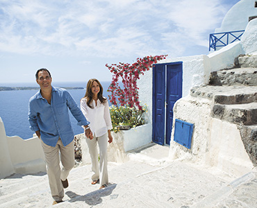 Par går hånd-i-hånd i en gate på Santorini, Hellas. Foto.