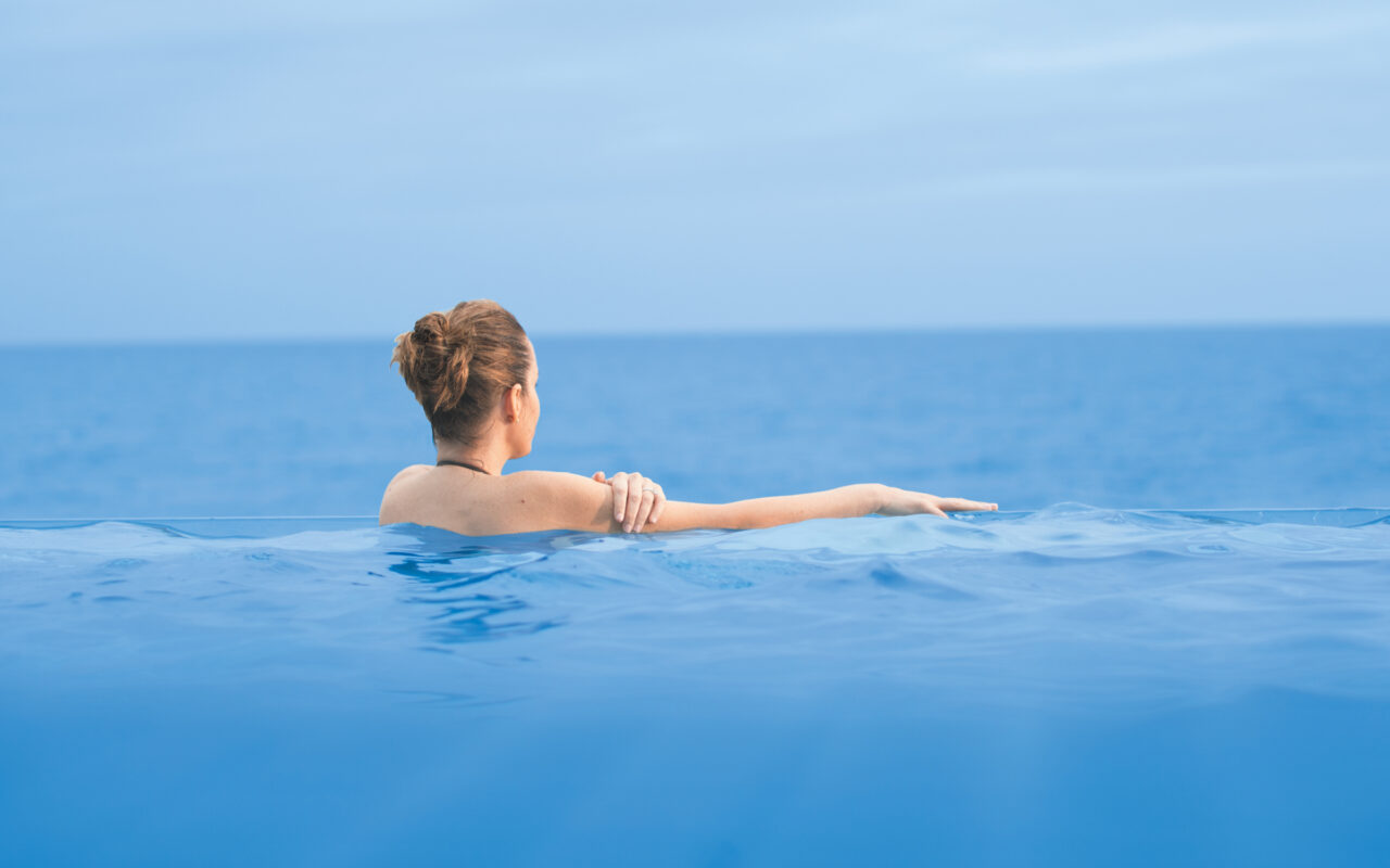 En kvinnelig cruisegjest ser ut mot havet fra et "infinity pool" om bord på Seven Seas Explorer. Foto.