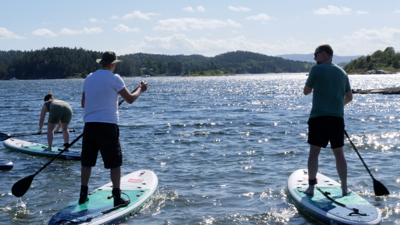 Deltakere står på SUP ute på vannet