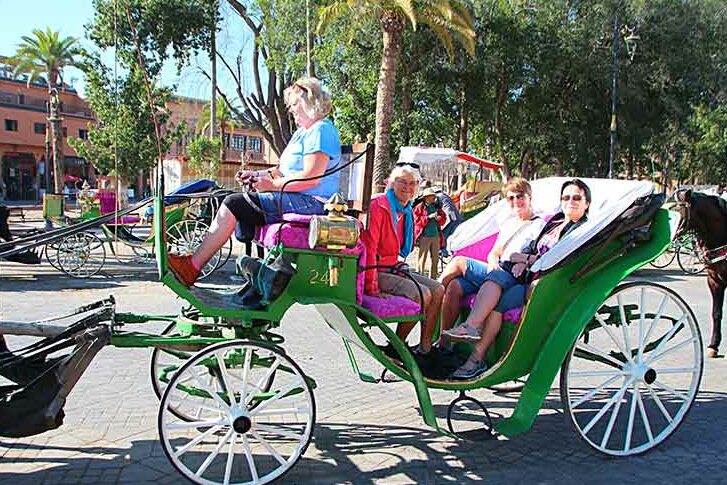 Turister sitter i en kjerre som dras av en hest i Marrakech