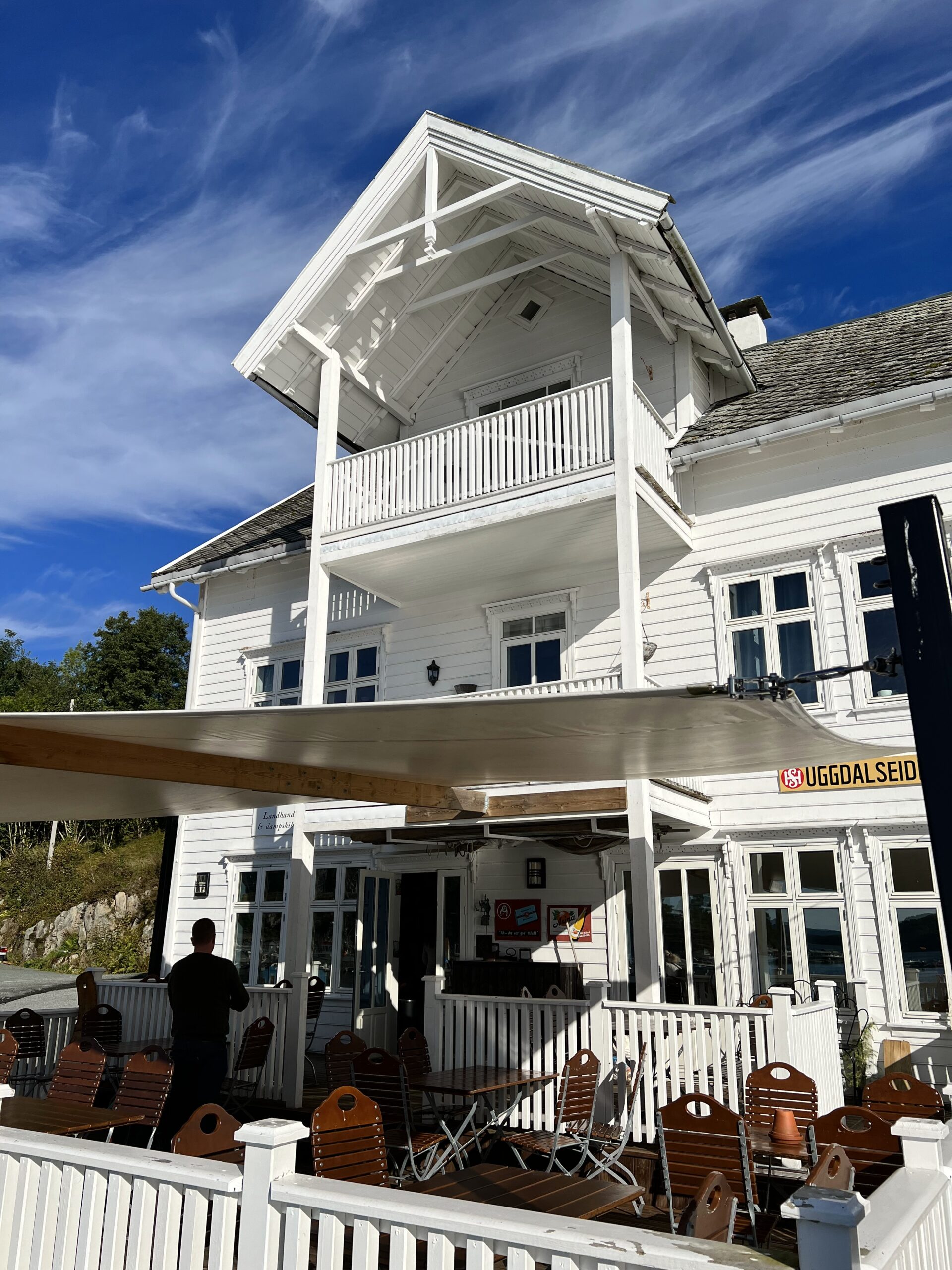 Hvitt trehus med terrasse og stoler foran