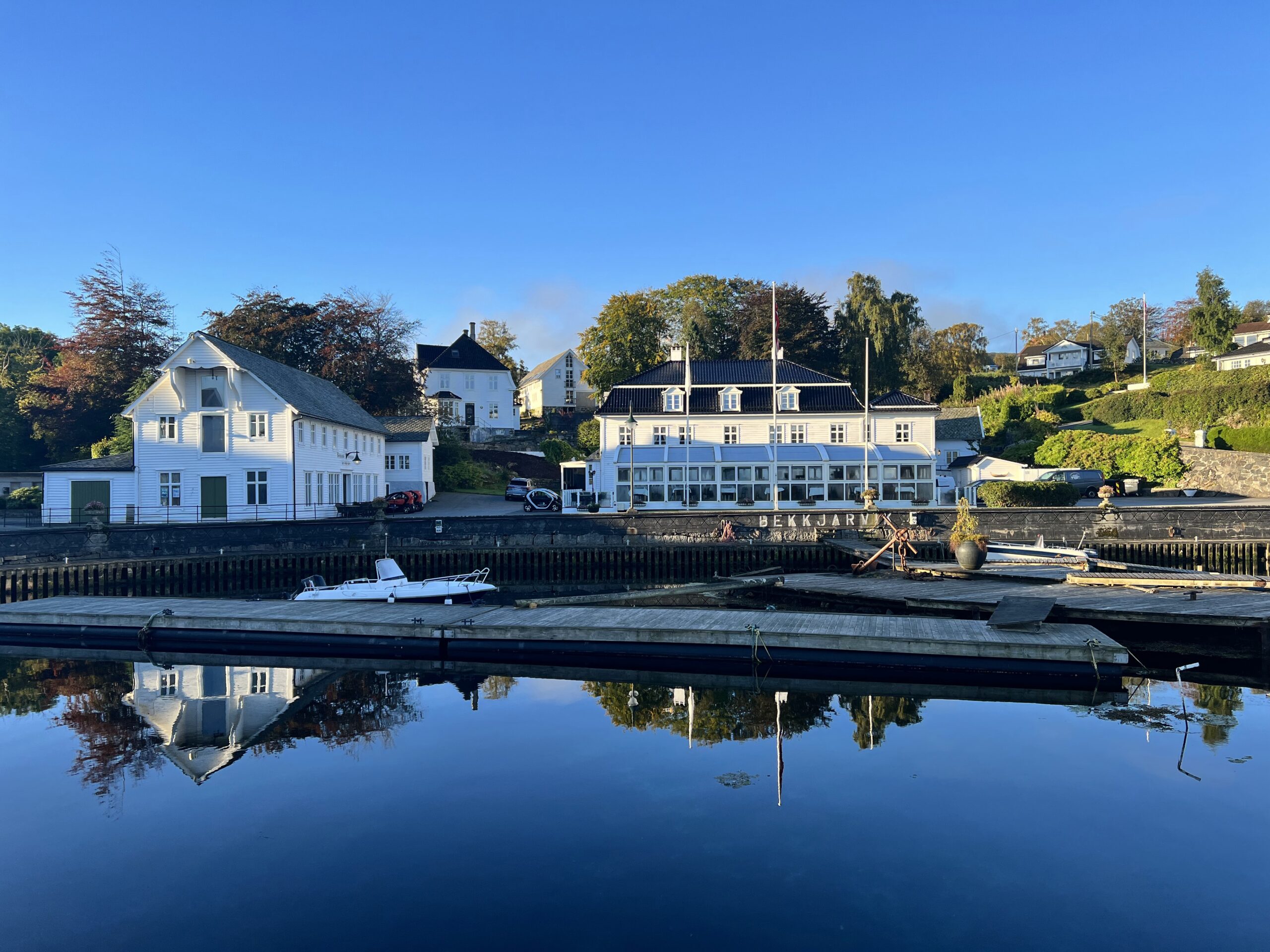 Hvit trehusbebyggelse idyllisk nede ved bryggen