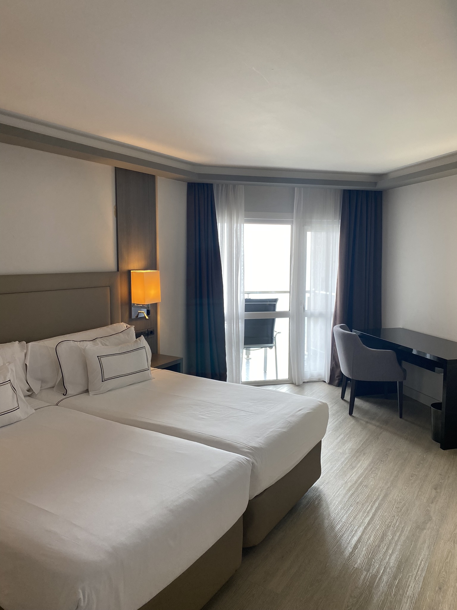 Hotellrom med lyse vegger, en skrivepult og dobbeltseng. Foto