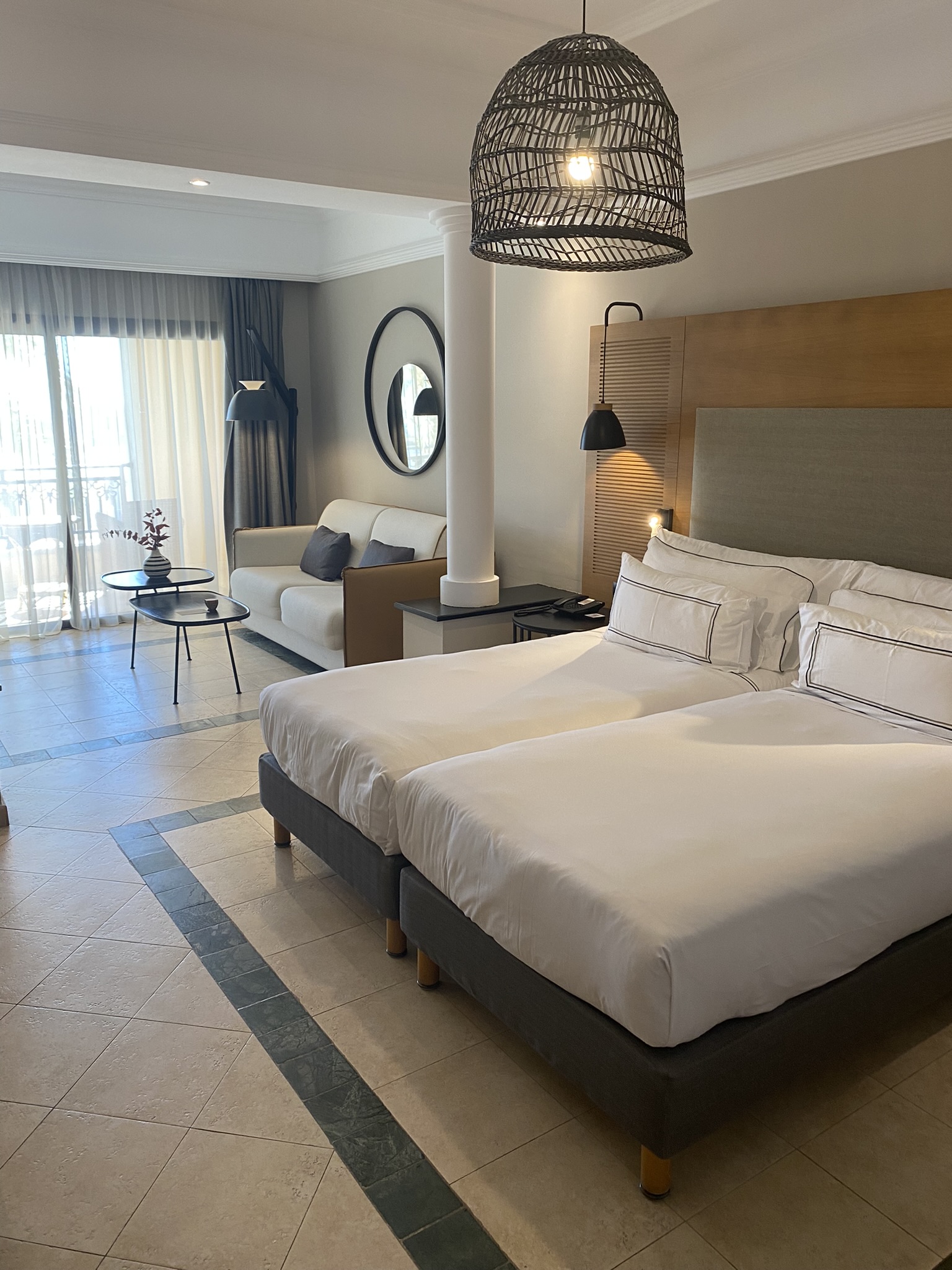 Stort hotellrom med duse farger og en stor dobbeltseng. Foto
