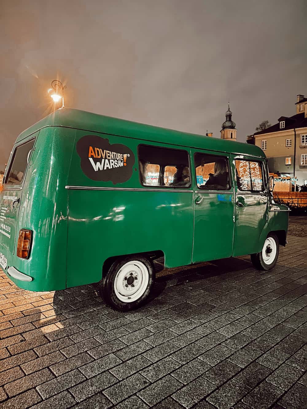 Grønn retro-van på et torg i mørket. Foto