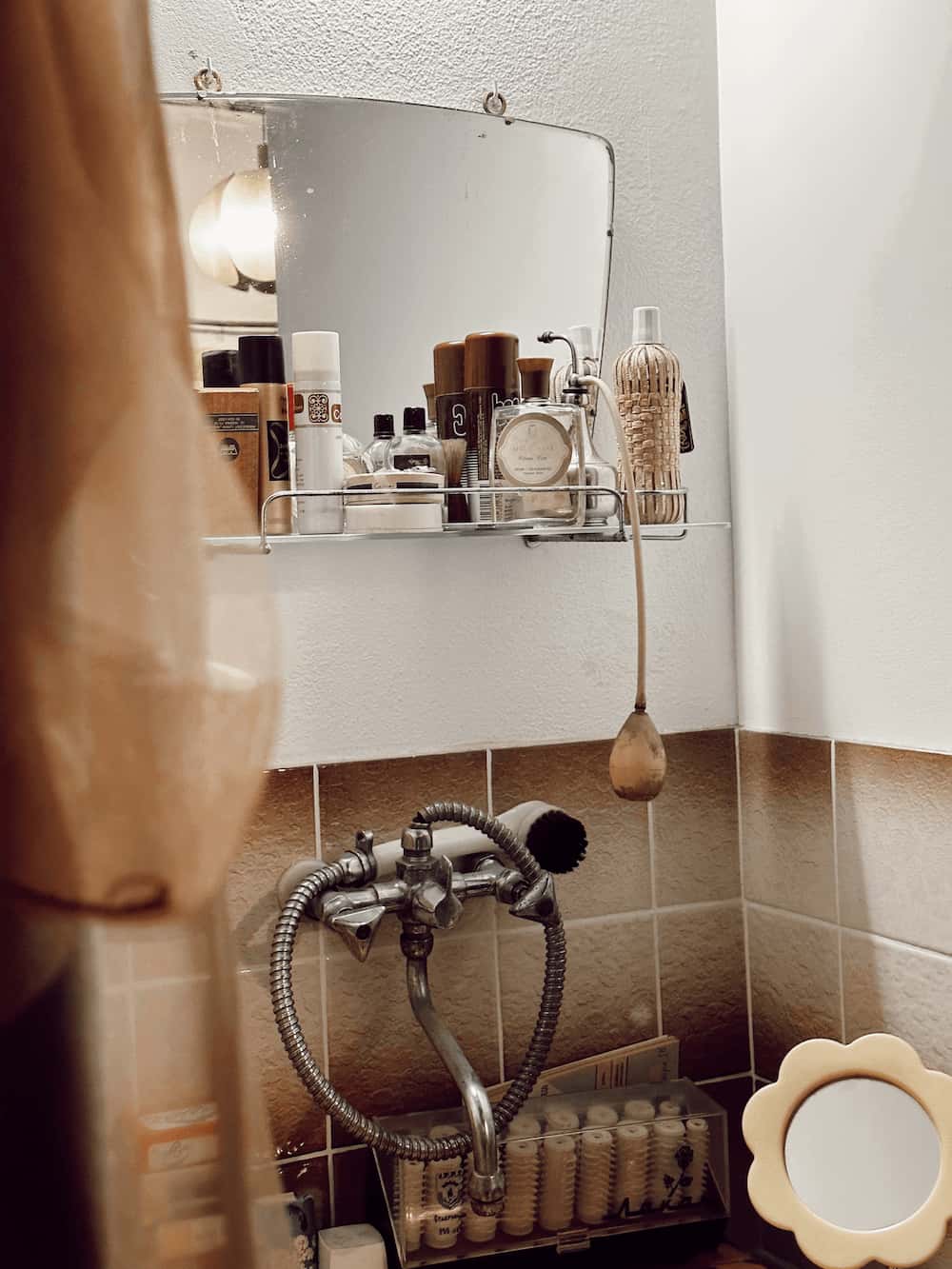 Et eldre bad med speil, skjønnhetsprodukter og dusj. Foto