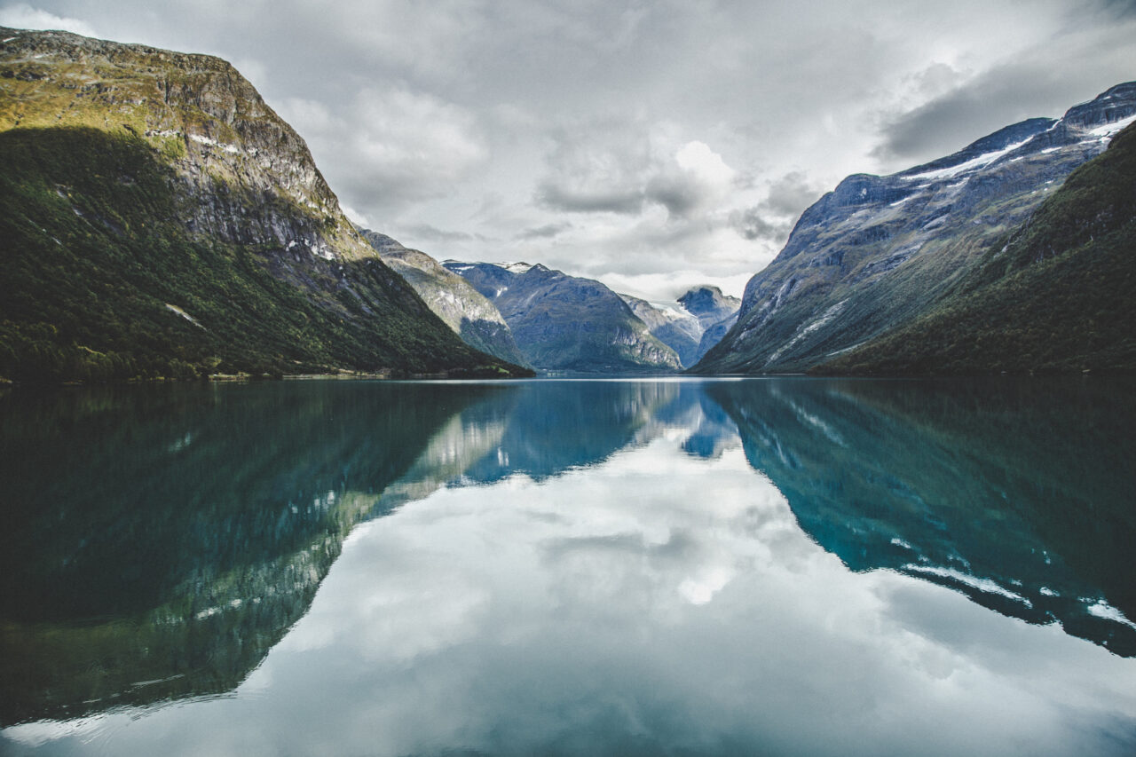 Klart vann og fjelltopper som skyter opp av fjorden. Foto