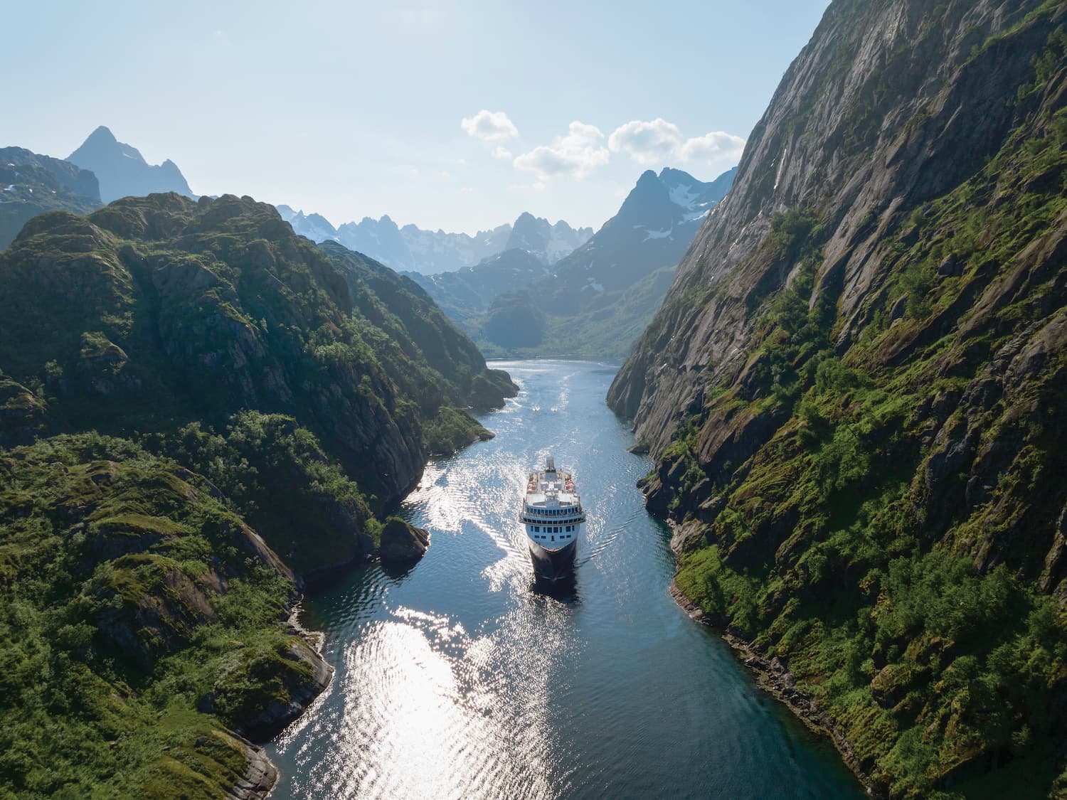 Cruiseskip seiler på en smal fjord og høye fjell. Foto