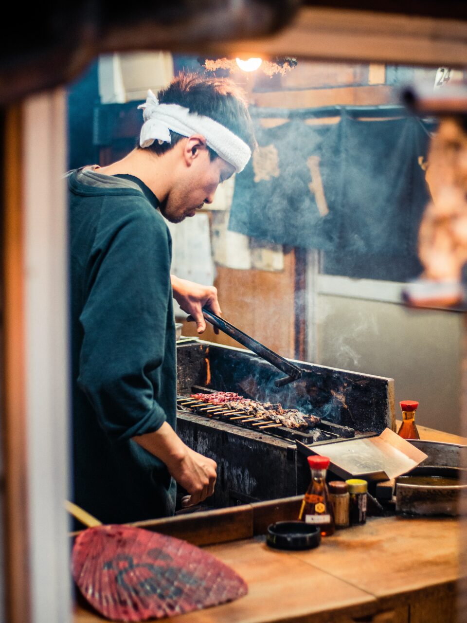 Kokk med ryggen til tilbereder grillspyd på grill. Foto