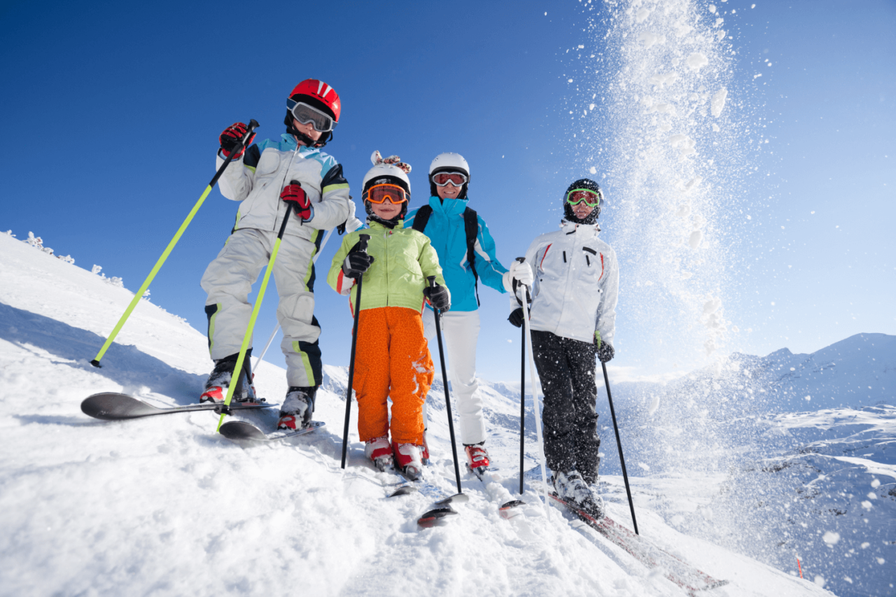 En familie i skibakken med slalåmski og skiutstyr. Foto