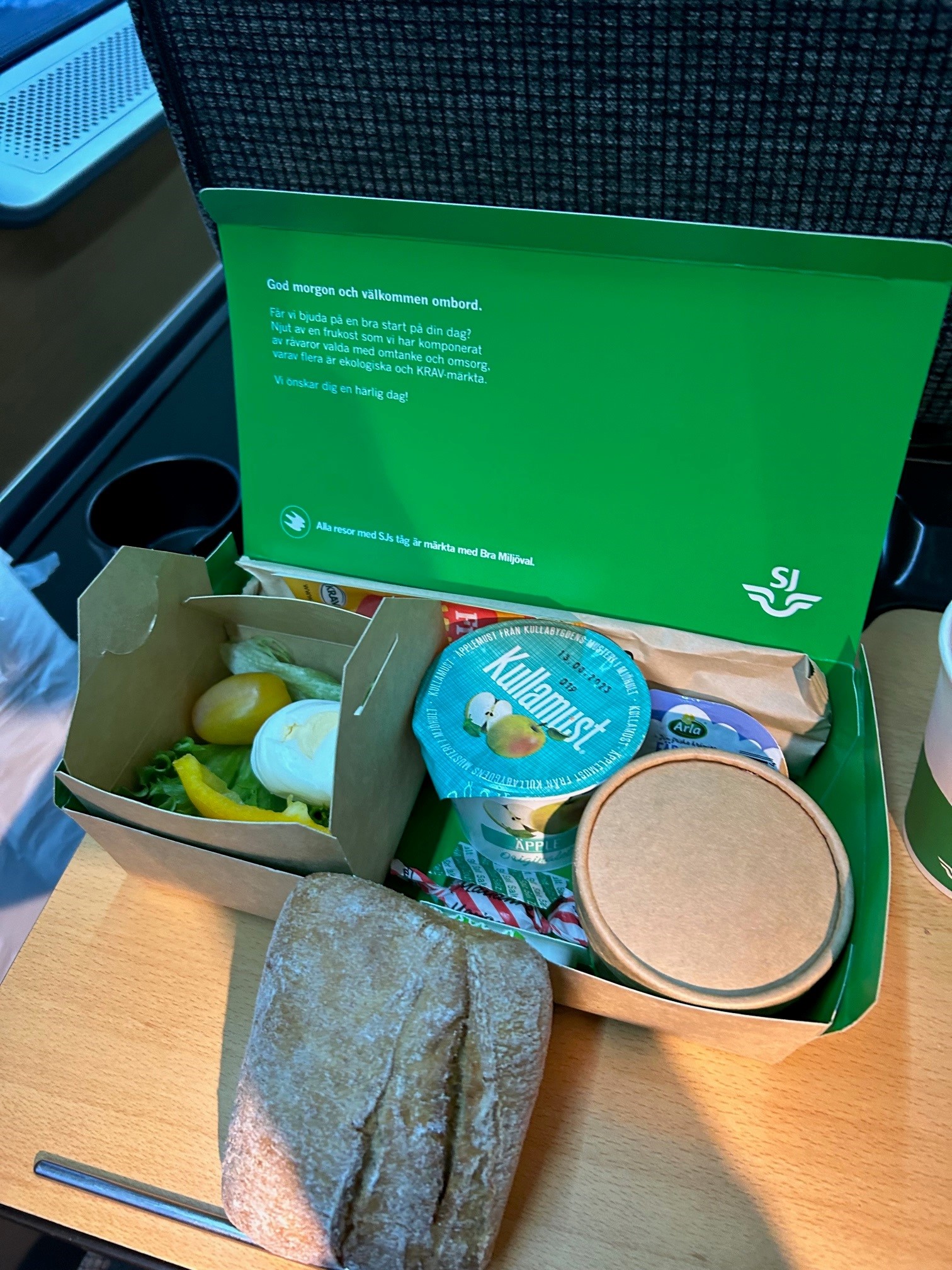 Grønn matboks med salat, yoghurt og brød. Foto