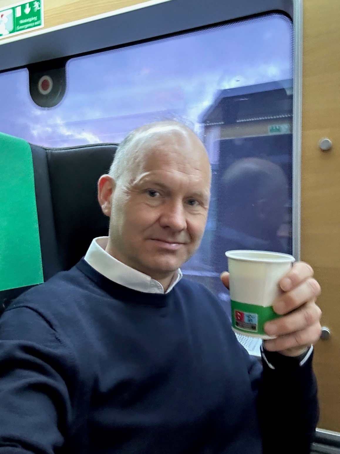 Mann sitter med kaffekopp ii hånden. Foto