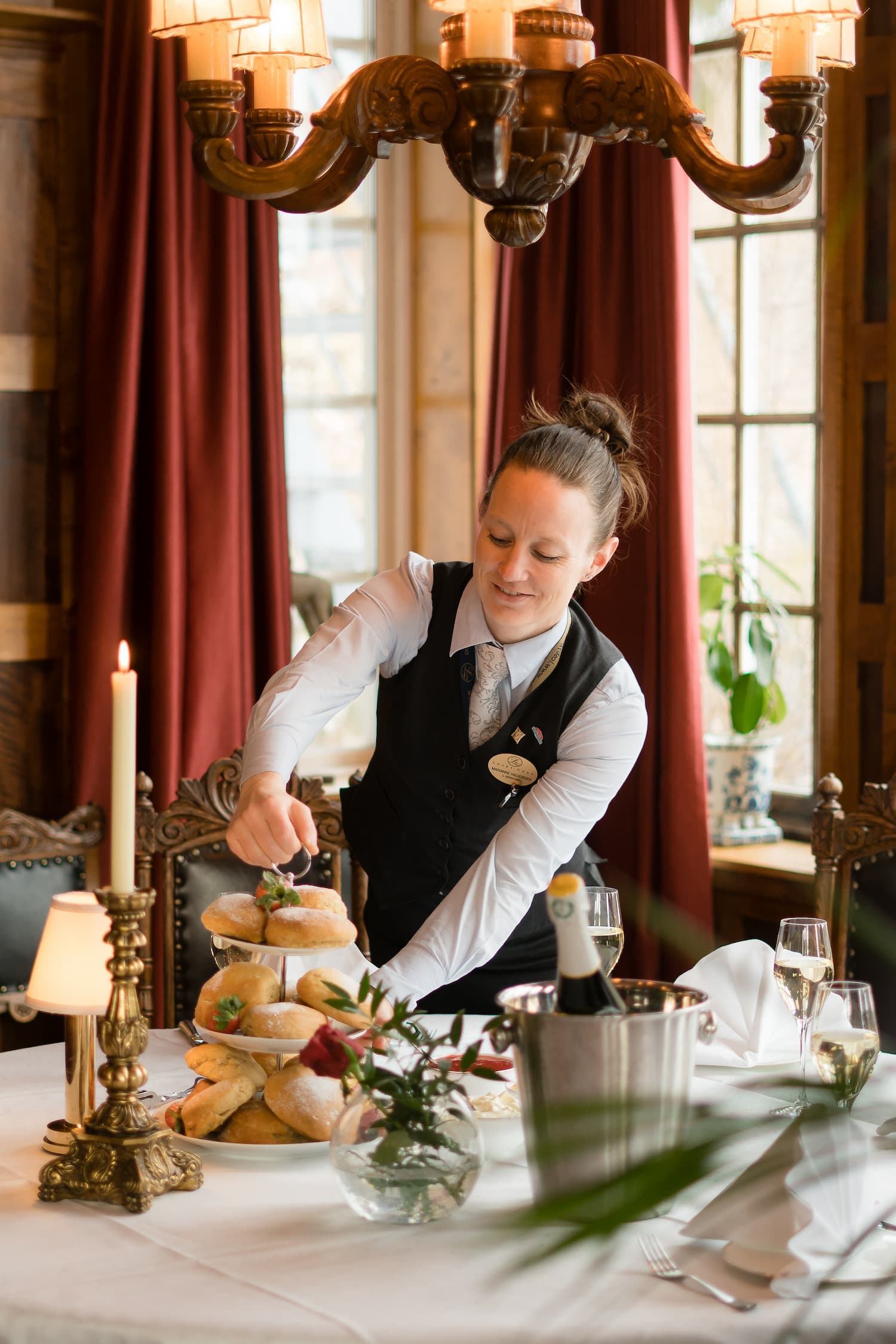 Kvinnelig servitør dekker et delikat bord i restaurant. Foto