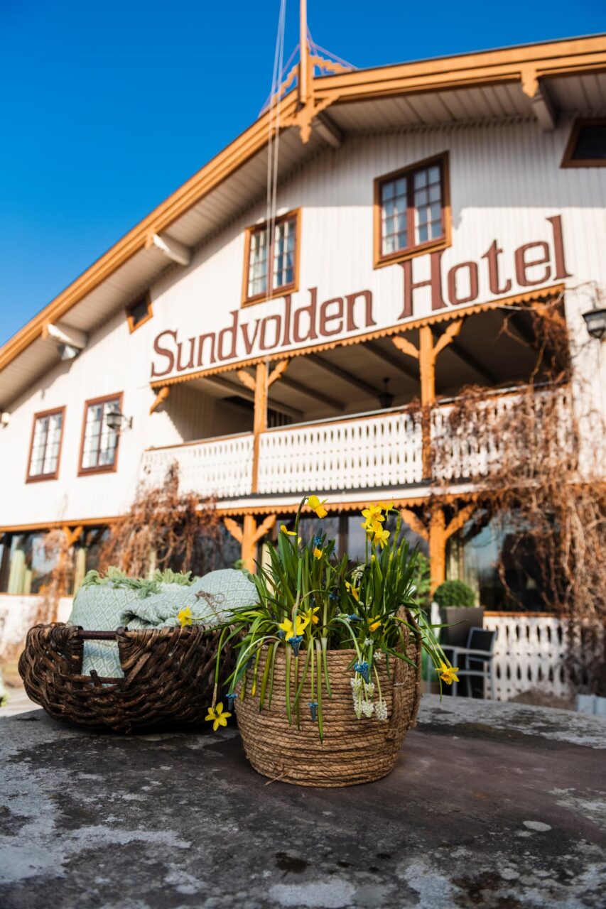 Hvitt trehus med bokstavene Sundvolden Hotel på. Foto