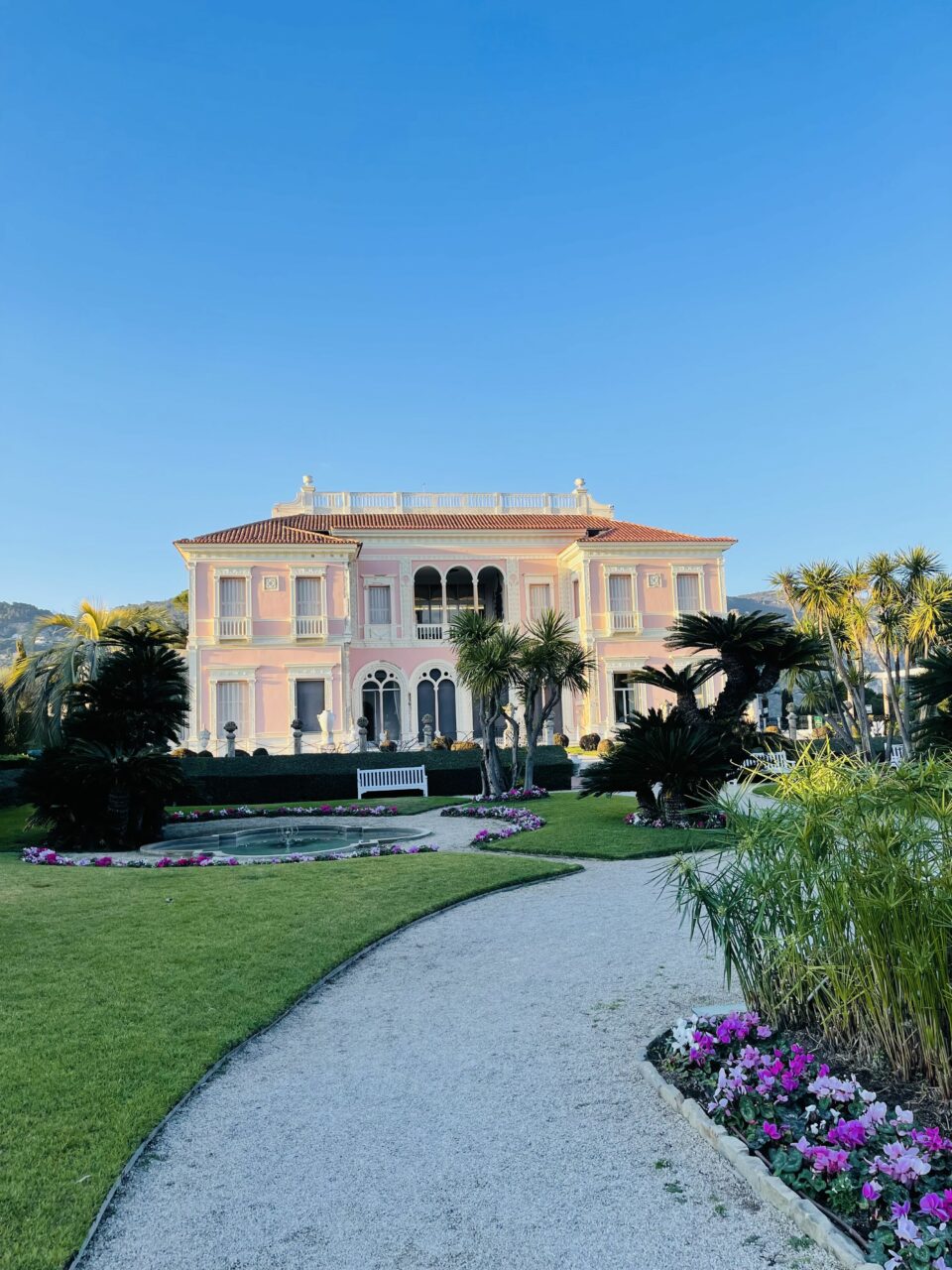 Et rosa, stort slott i en frodig og fargerik hage. Foto