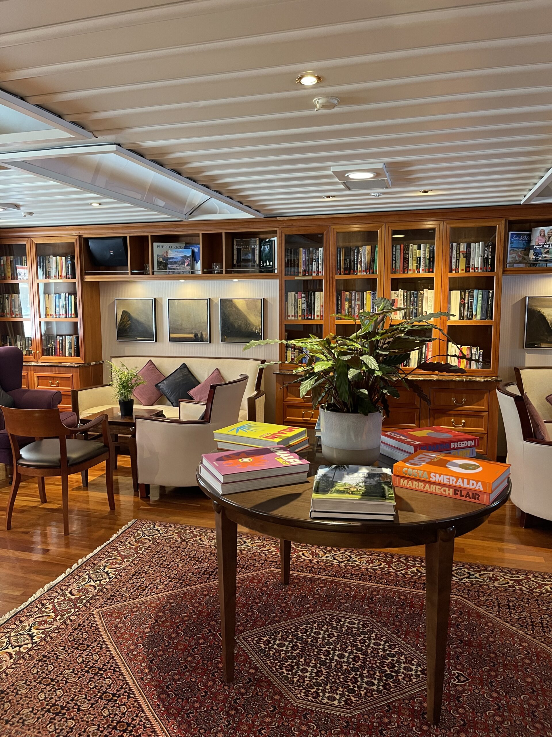 Bibliotek med hyller fulle av bøker og møblement i mørk tre. Foto