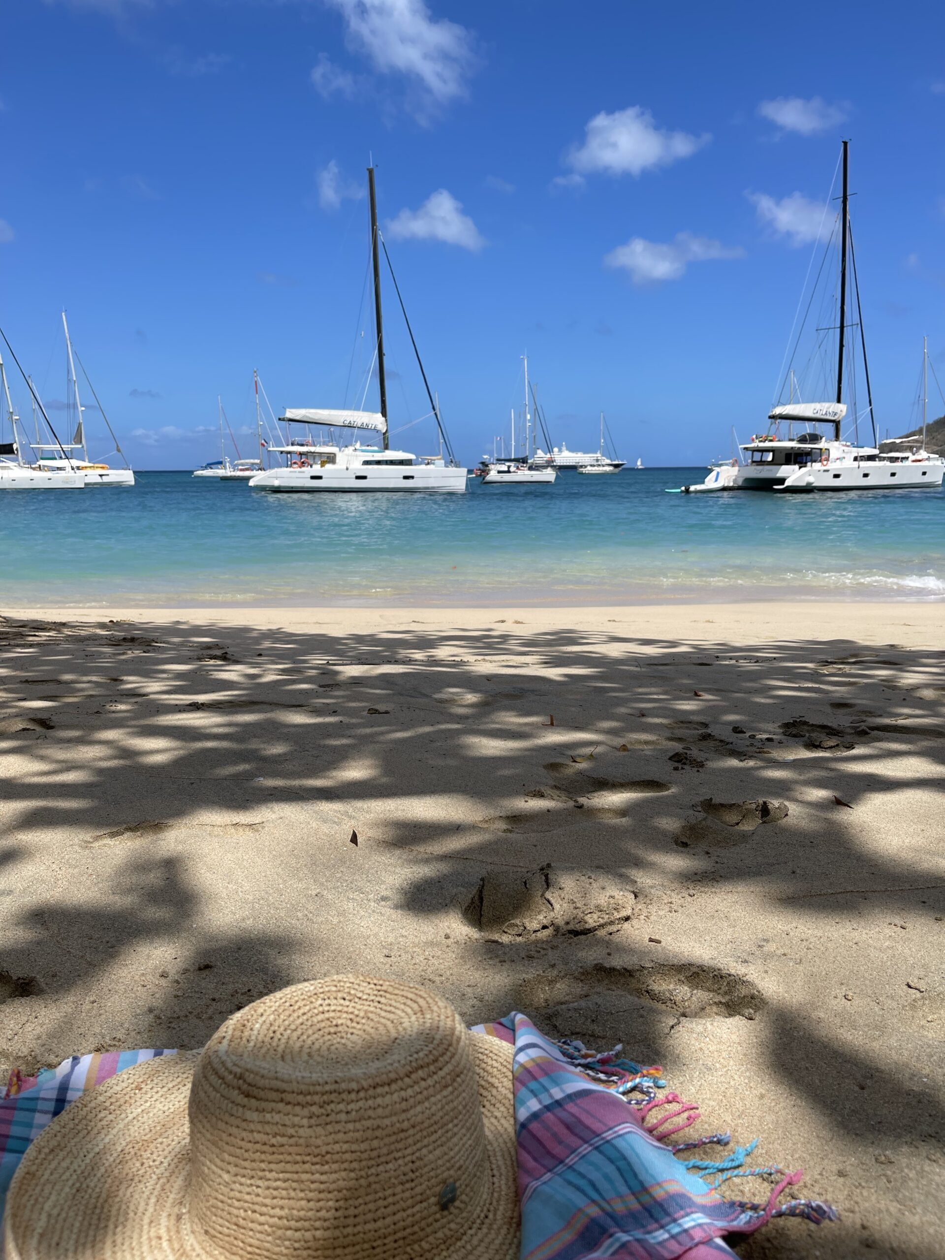 En solhatt som hviler på en sandstrand ut mot havet. Foto