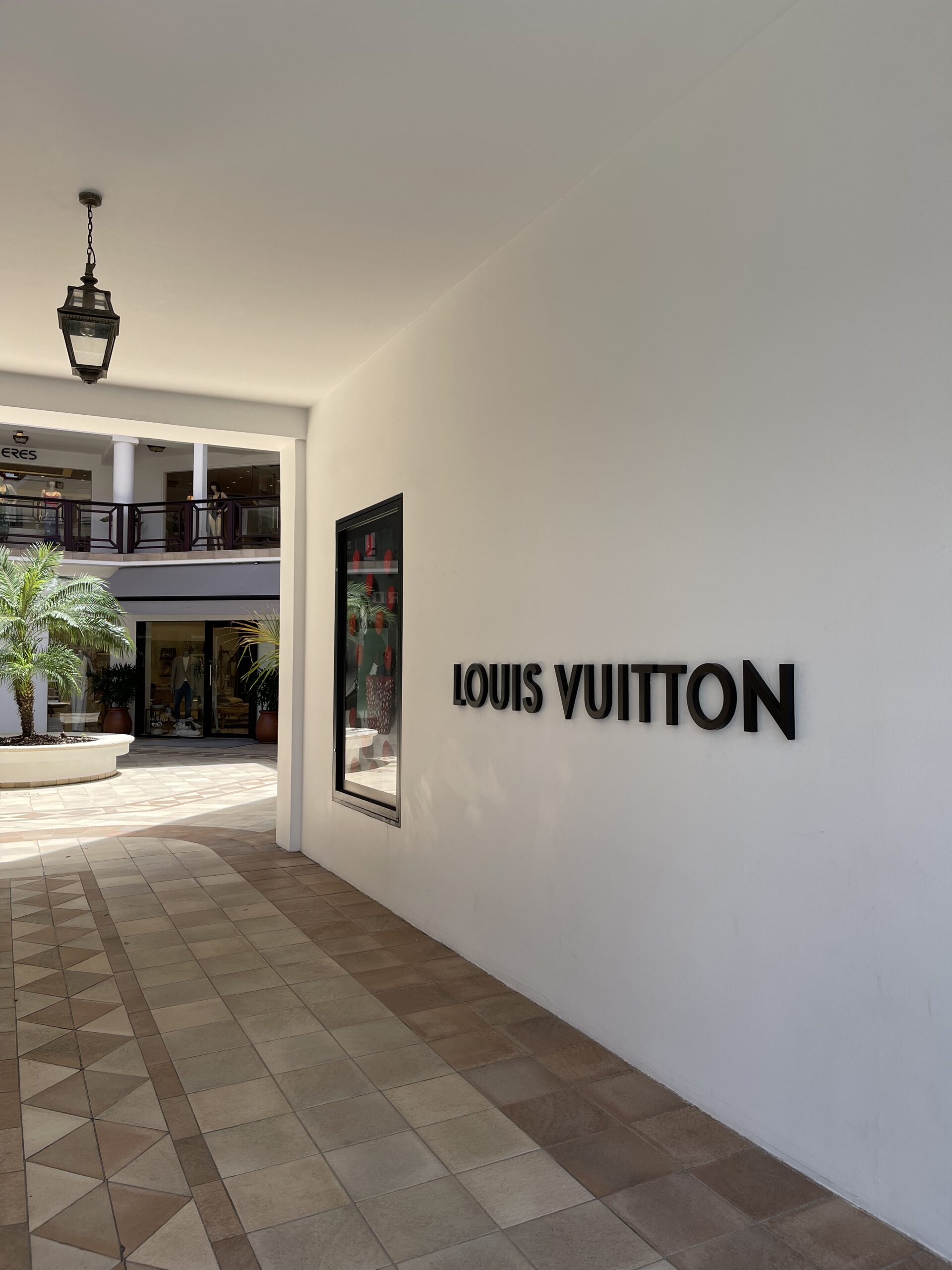 En hvit vegg med følgende tekst: "Louis Vuitton". Foto