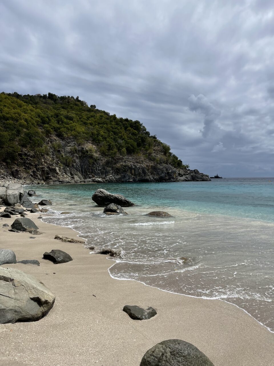 En vakker sandstrand med steiner og blått hav. Foto