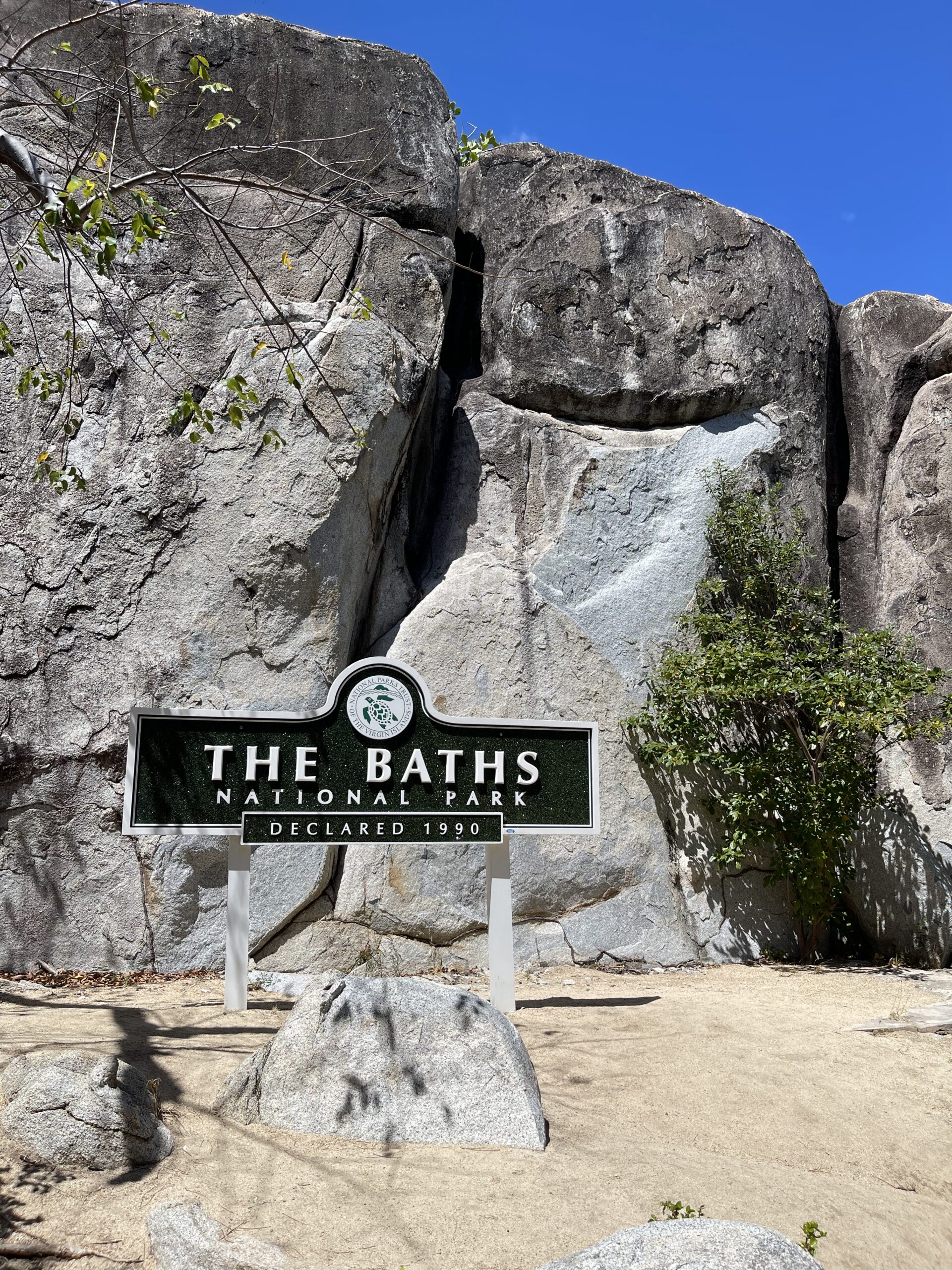 Et skilt med teksten "The Baths" som peker vei mot et fjell. Foto