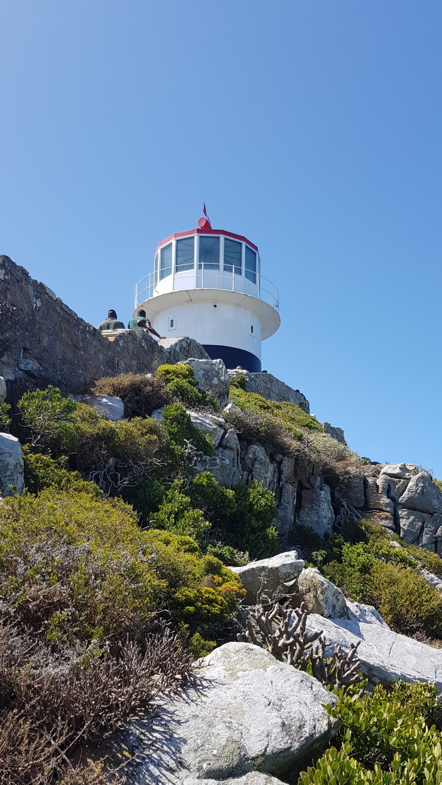 Hvitt fyrhus på toppen av en klippe. Foto
