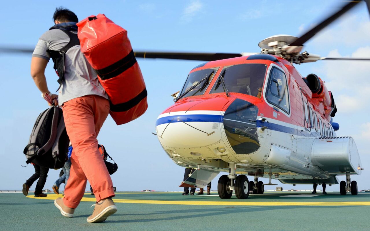 Mann med bag på ryggen på vei inn i et helikopter. Foto