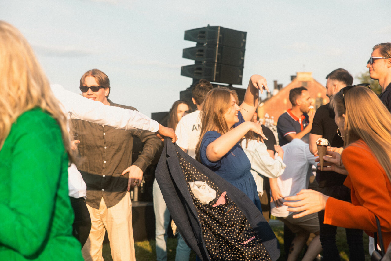 Feststemte mennesker danser og spiser is i fint sommervær. Foto