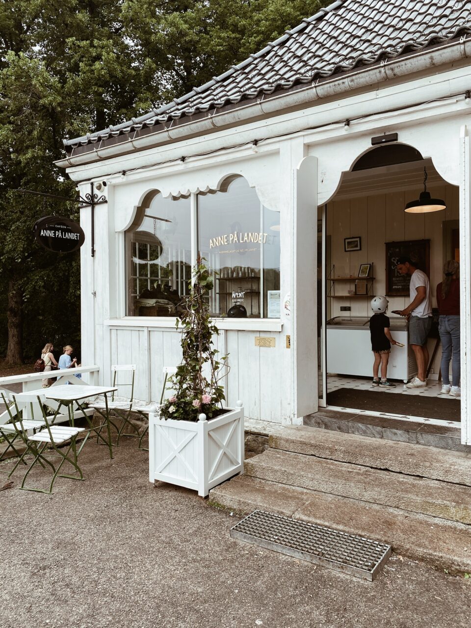 Et hvitt hus utenfra med en hyggelig inngang til en cafe. Foto