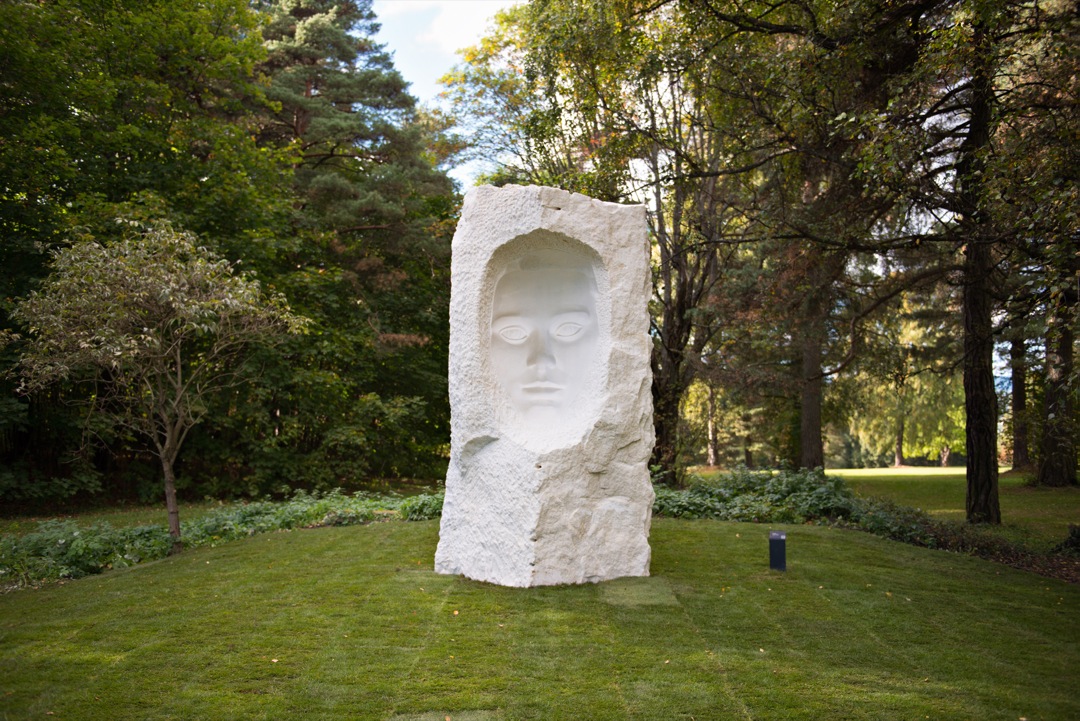 En skulptur av et ansikt i en stein plassert i naturen. Foto