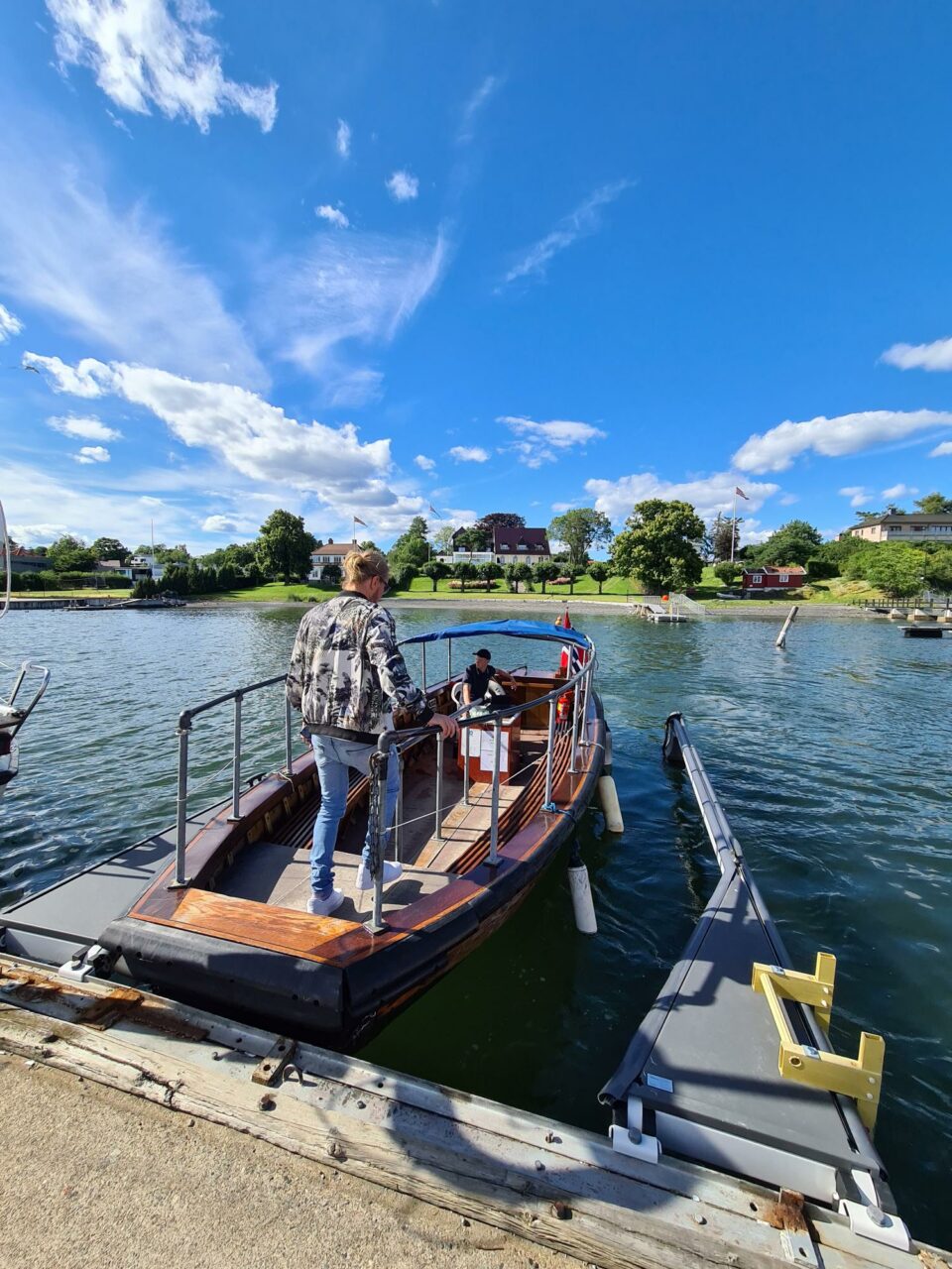 En eldre trebåt til kai på vei over vannet til en liten øy. Foto