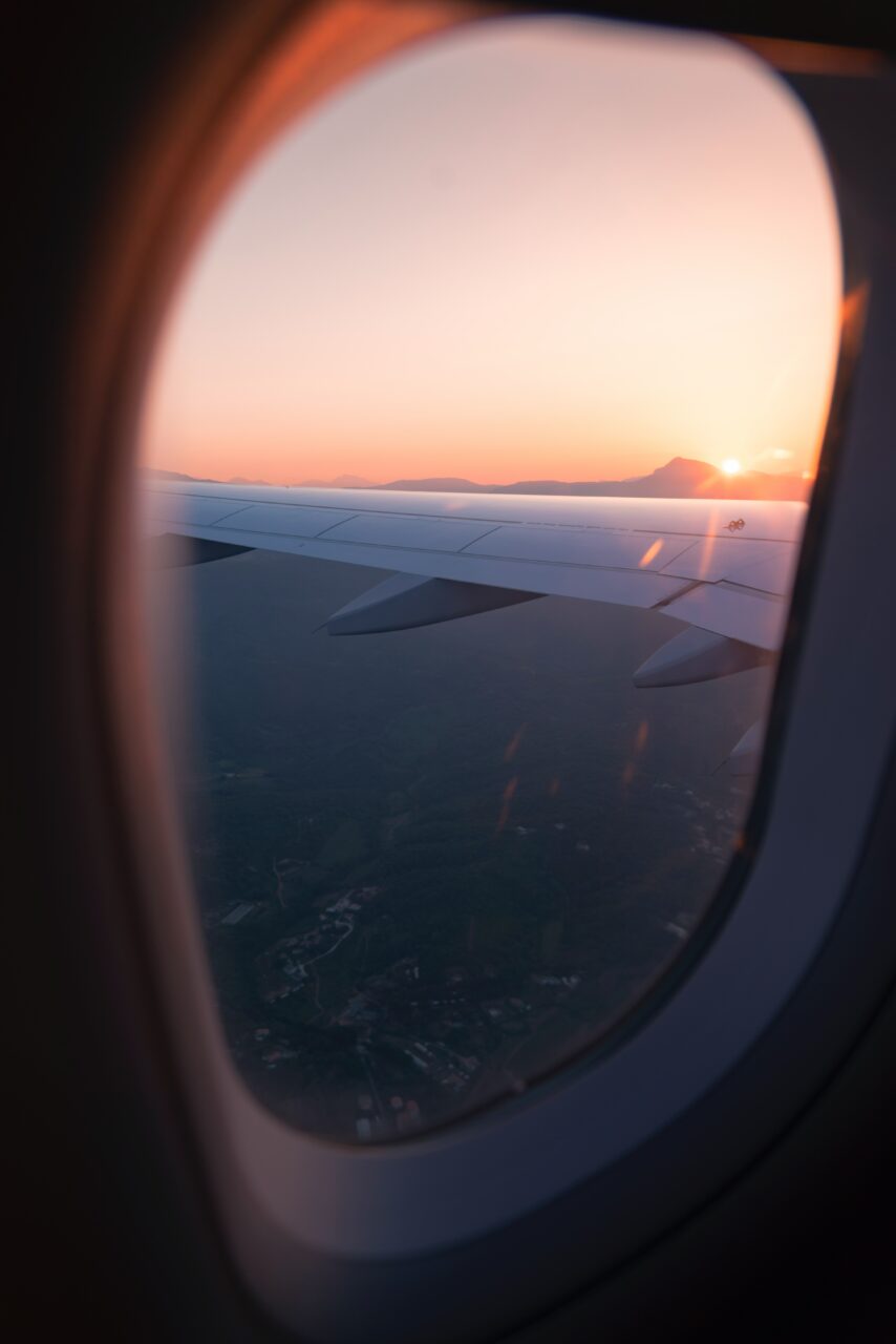 Bilde ut et flyvindu i soloppgang. Foto