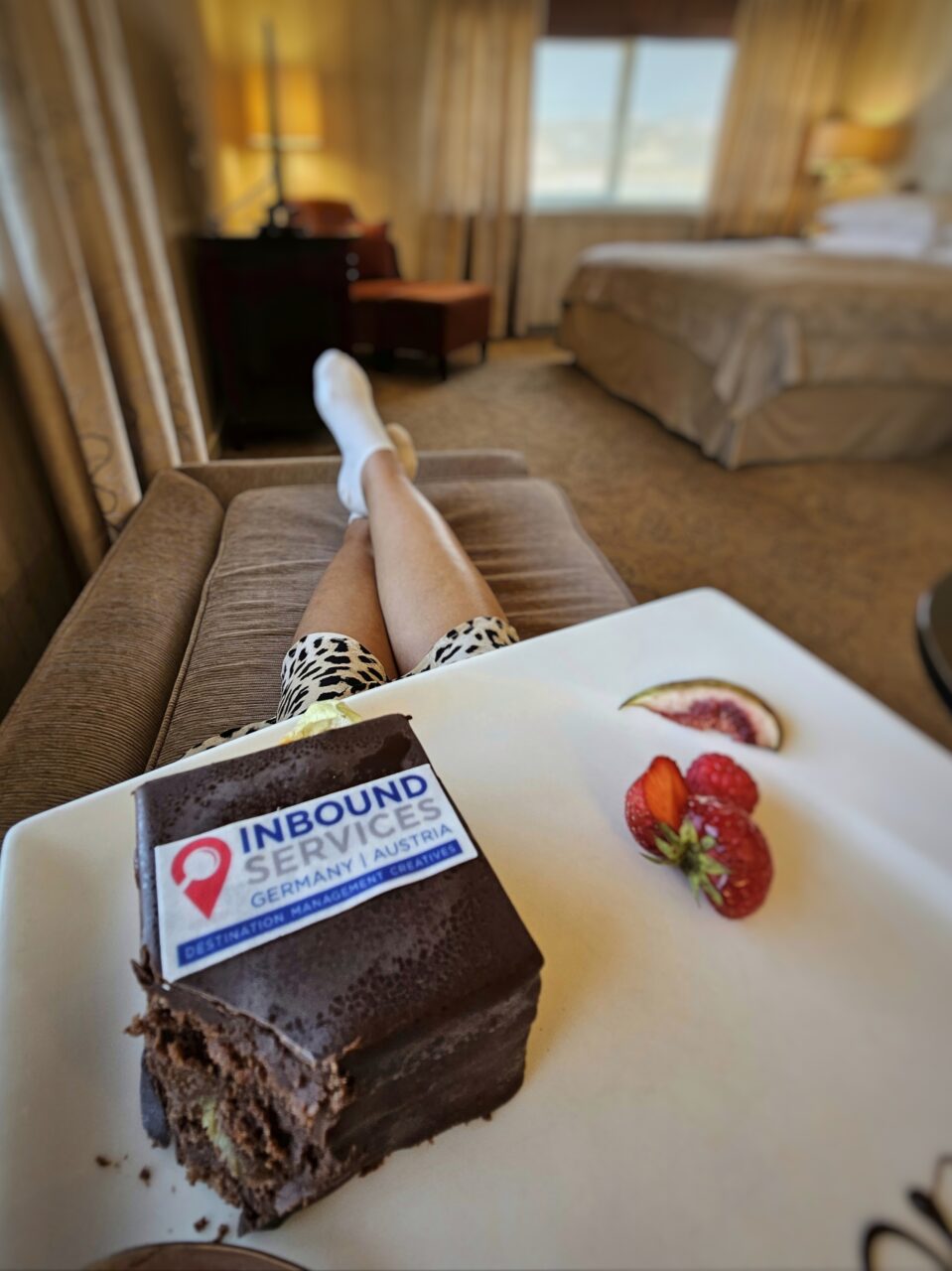 Kvinne sitter på sofa med kake i fanget. Foto