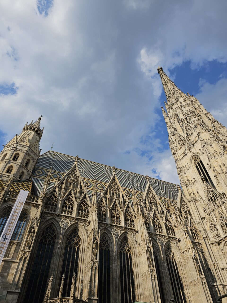Stor kirke i stein med stripete tak og høyt tårn. Foto