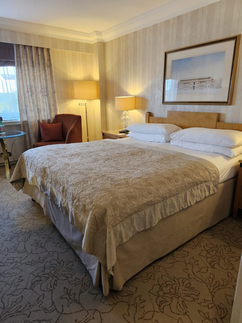 Dobbeltseng på hotellrom med lyse farger. Foto